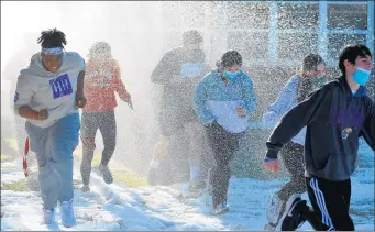  ?? JEFF VORVA/DAILY SOUTHTOWN ?? Instead of plunging into Lake Michigan, Marist High School students ran through a spray of icy cold water during a Special Olympics fundraiser at the school Tuesday.