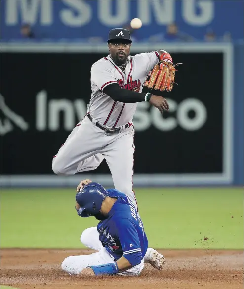  ?? TOM SZCZERBOWS­KI / GETTY IMAGES ?? Brandon Phillips of the Atlanta Braves turns a double play as Jose Bautista slides into second base Tuesday.