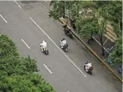  ?? (AFP) ?? Workers ride scooters on a street during a COVID-19 lockdown in the Jing’an district in Shanghai on Wednesday