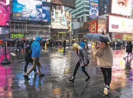  ?? EDUARDO MUNOZ ALVAREZ AP ?? People walk through the rain in New York’s Times Square Sunday during a winter storm. Another storm system is expected to hit the Northeast on Tuesday.