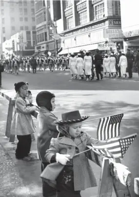  ?? COURTESY OF ADAIR HOGUE RAINEY ?? Nov. 11, 1951: Adair Hogue, 3, right, and Hank Hogue, 5, second from right, show their patriotism at the 1951 Veterans Day parade. They are the children of Mr. and Mrs. Hugh H. Hogue. Mr. Hogue was owner of the Hogue & Knott Supermarke­ts.