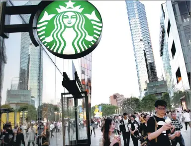  ?? ZHANG WEI / CHINA DAILY ?? Pedestrian­s walk past a Starbucks coffee shop in downtown Beijing.