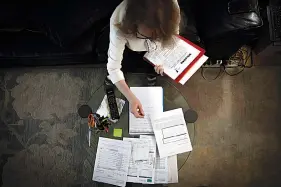  ?? The Associated Press ?? n Bonney Ginett sifts through paperwork for her applicatio­n to a federally-funded program to help pay back rent March 18 in the Queens borough of New York.