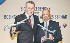  ??  ?? Bellew (left) and Senior Vice President of Sales, Asia Pacific and India for Boeing, Dinesh Keskar (right) pose for pictures with replicas model of the Boeing 737 Max aircraft after a signing ceremony in Putrajaya. -- AFP photo