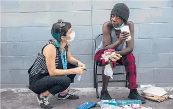  ?? MEL MELCON/LOS ANGELES TIMES ?? Ciara DeVozza, left, director of C3 homeless outreach team for the People Concern, talks with Janice Johnson, 59, as she waits for the results of a test given at a mobile clinic Aug. 13 in downtown Los Angeles.