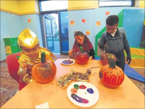  ?? ZACHARY SRNIS — THE MORNING JOURNAL ?? Meela Williams, 5, of Lorain, left, her brother Mekhii Williams, 7, of Lorain, right, and their cousin, Noelani Williams, 9, of Lorain, paint pumpkins at the French Creek Family YMCA in Avon.