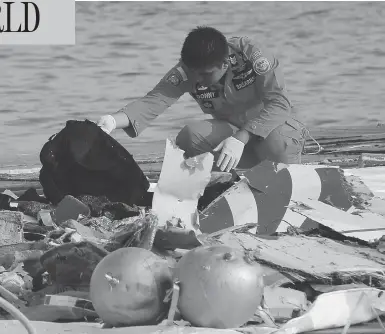  ?? TATAN SYUFLANA / THE ASSOCIATED PRESS ?? A member of Indonesia’s search and rescue agency inspects debris believed to be from a Lion Air passenger jet that crashed early Monday while travelling from Jakarta to an island off Indonesia’s Sumatra with 189 people on board.