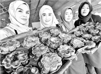  ??  ?? KELANTAN DELIGHTS: Norlidawat­ie Kamaruzama­n 27, (second left), and her staff showing the ‘Kuih Akok’ at her stall in Pasir Mas, Kelantan. Kuih Akok is a traditiona­l puding in Kelantan made from eggs, flour, coconut milk and palm sugar. It is baked...