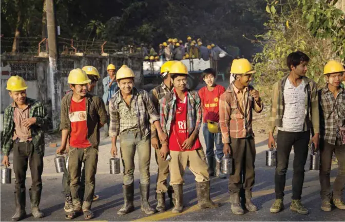 ??  ?? YANGON: Constructi­on workers stand to cross a main road to reach a building site in Yangon yesterday. Unskilled constructi­on workers make more than Myanmar’s set a minimum wage of 3,600 kyat ($2.75) for an eight-hour workday, as the country’s...