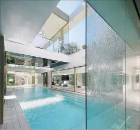  ??  ?? MOTORIZED GLASS walls open to an indoor pool and one outdoors. The home also has a 20-foot waterfall feature.
