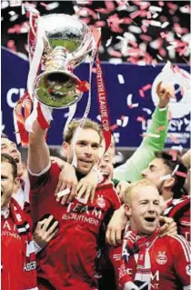  ??  ?? 2015: Dons captain Russell Anderson raises the League Cup trophy after victory against Caley Thistle. Different competitio­n, same outcome on Saturday, please