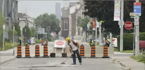  ?? PHOTOS BY SCOTT GARDNER, THE HAMILTON SPECTATOR ?? A worker on Balsam Avenue cleans the road by a barrier closing the street at Cannon.