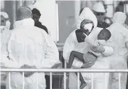  ?? AP PHOTO/JONATHAN BORG ?? A child is disembarke­d from the ship operated by German aid group Mission Lifeline after it docked Wednesday at the Valletta port in Malta awaiting permission to make landfall.