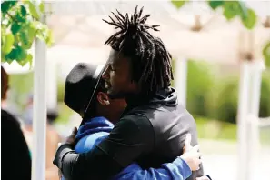  ?? The Associated Press ?? Buffalo Bills’ Josh Thomas, right, embraces a person Wednesday as he visits the scene of Saturday’s shooting at a supermarke­t in Buffalo, N.Y.