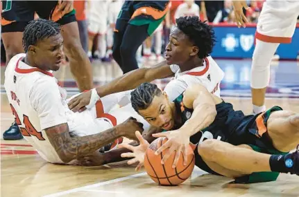  ?? KARL B DEBLAKER/AP ?? Miami’s Isaiah Wong (2) tries to gather in a loose ball with North Carolina State’s Ernest Ross (24) and Jarkel Joiner, back, nearby during the second half of Saturday’s game in Raleigh, N.C.