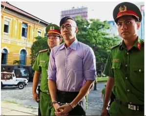  ?? — AFP ?? Not welcome: Policemen escorting Nguyen to the courthouse in Ho Chi Minh City. He has been ordered to leave Vietnam.