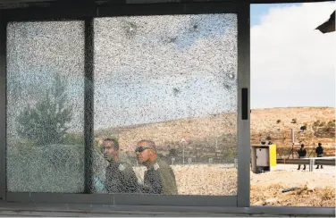  ?? Menahem Kahana / AFP / Getty Images ?? Israeli security forces examine glass shattered by bullets in a shooting at the Har Adar settlement.