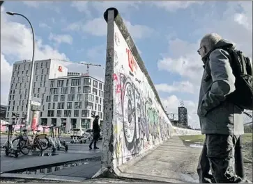  ?? Carsten Koall Getty Images ?? TOURISTS view a former section of the Berlin Wall as Germany prepares to mark the 30th anniversar­y of the fall of the barrier separating East and West Berlin. Reminders of the split have lasted into the new century.