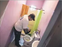  ??  ?? JORGE RESENDIZ pours water into a toilet in his home, where there is no running water, in the Puerto Azul tract in Ensenada.