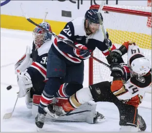  ?? MANUEL BALCE CENETA ?? The Capitals’ Nic Dowd, center, knocks down the Ducks’ Adam Henrique, right, while Capitals goaltender Darcy Kuemper reaches for the puck during Tuesday’s game at Washington. The Ducks lost 2-0.