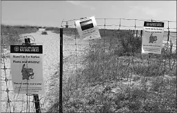  ?? Associated Press ?? Signs are posted asking Pokémon Go players to stay on the path instead of walking through the grass to protect wildlife at the Loyola Dunes area on Chicago's lakeshore.