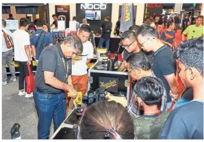  ??  ?? All about wheels: A Meguiar technician demonstrat­ing the applicatio­n of a car care product and Tint Auto workers (right) showing how to apply Llumar automotive film on a Ferrari at KLIMS’18 in Kuala Lumpur.