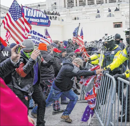 ?? John Minchillo The Associated Press ?? Trump supporters try to break through a police barrier on Jan. 6, 2021, at the Capitol in Washington.