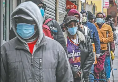  ??  ?? People wait April 18 for a distributi­on of masks and food in the Harlem neighborho­od of New York.