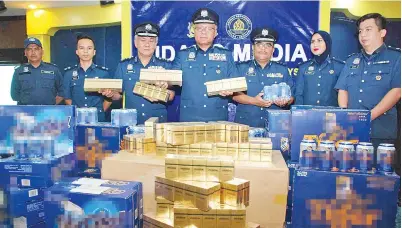 ??  ?? ZULKIFLI (tengah) menunjukka­n rokok serta minuman keras bernilai lebih RM10 juta yang dirampas dalam tiga serbuan berasingan di Kota Kinabalu dan Penampang.