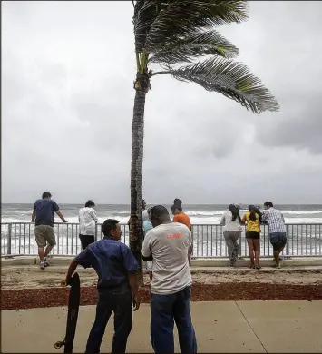  ?? BRUCE R. BENNETT / THE PALM BEACH POST 2016 ?? Storm watchers visit Lake Worth Beach as winds from Hurricane Matthew begin to pick up in October. Some meteorolog­ists say a slashed budget could leave citizens more vulnerable because they will have less storm informatio­n.