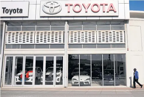  ?? REUTERS ?? A man walks past a closed Toyota dealership in Cape Town on April 28.