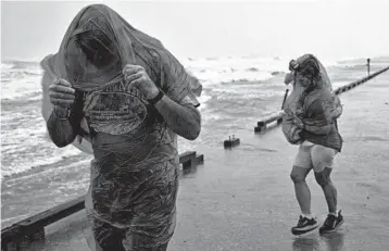  ?? COURTNEY SACCO/CORPUS CHRISTI CALLER-TIMES ?? People walk along the seawall to watch as Hurricane Hanna approaches land Saturday in Corpus Christi, Texas.