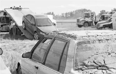  ?? Lorraine Hjalte/ Postmedia News ?? A car that was buried in mud sits in a secure lot in High River while more vehicles are towed in.