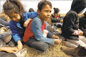  ?? Photograph­s by Carolyn Cole Los Angeles Times ?? CHRISTOPHE­R GARCIA, 10, center, sits with fellow Central American migrants in the Rio Grande Valley of Texas on March 25 while awaiting transport to a U.S. Customs and Border Protection holding area.