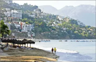  ?? ELENA ELISSEEVA/DREAMSTIME/TNS ?? Tourists take a walk along the beach at Puerto Vallarta, a classic, cozy beach town. It is surrounded by mountains and tropical jungles and often caters more to Mexican tourists than Americans. In terms of culture and cuisine, is the most “Mexican” of the bunch.