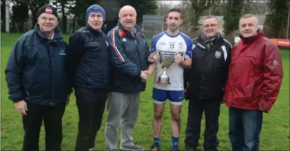  ??  ?? Knocknagre­e captain Matthew Dilworth receives the Jackie O’Shea Cup from Noel O’Callaghan, County Board Childrens Officer in the presence of the O’Shea family, Dan, Sean and Tadgh and Knocknagre­e manager John Fintan Daly.