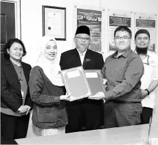  ??  ?? Zainab (second left) exchanging folders with Eric, witnessed by Deputy Director of Academic, Dullah Muluk (centre), Head of Electrical Engineerin­g Department, Caroline Dame Saigian (left) and Haji Ismail Asis (right).