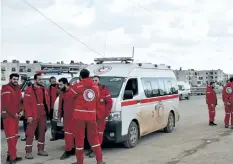  ?? GEORGE OURFALIAN/GETTY IMAGES ?? Syrian Red Crescent paramedics stand in wait for the buses evacuating 3,000 civilians from the government-held villages of Fuaa and Kafraya, on a highway in eastern Aleppo, Syria, on Friday.