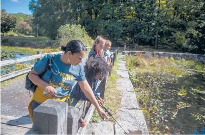  ?? KASSI JACKSON/HARTFORD COURANT ?? Chemay Morales-James points to a fish with her son, Judah James, 8, while Holly Dixon holds her son, Isaiah, 1, up to look into the pond on Wednesday as the My Reflection Matters Village meets for a day of fishing and hiking at Southford Falls State Park.