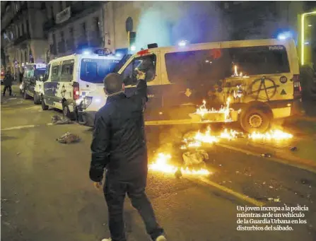  ??  ?? Un joven increpa a la policía mientras arde un vehículo de la Guardia Urbana en los disturbios del sábado.