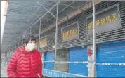  ??  ?? GHOST TOWN: A woman walks past shuttered shops in Wuhan.
AFP