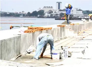  ?? PHOTOGRAPH COURTESY OF PNA ?? WORKERS place tiles along the sidewalk of Roxas Boulevard in Manila, as part of the government’s effort to rehabilita­te the Manila Bay area.