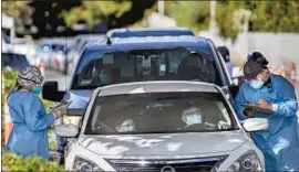  ?? Gina Ferazzi Los Angeles Times ?? HEALTHCARE WORKERS gather patient informatio­n before administer­ing coronaviru­s tests at a drive- through testing site last week in Riverside.