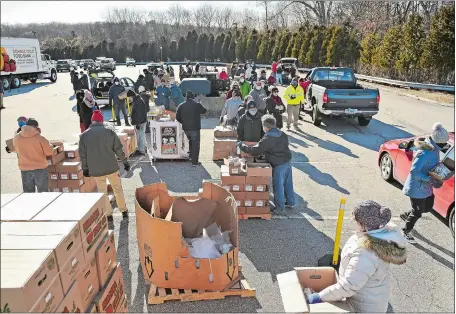  ?? SEAN D. ELLIOT/THE DAY ?? Volunteers load food into cars at a Connecticu­t Food Bank/Foodshare distributi­on Monday in Norwich. About 45 volunteers and 40,000 pounds of food were in place for those in need at the former Foxwoods employee parking lot on Route 2.