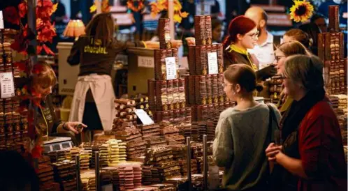  ?? CHRISTOPHE ENA/ASSOCIATED PRESS (ABOVE); LISA ZWIRN FOR THE BOSTON GLOBE (BELOW) ?? Left: Visitors bought treats at the Salon du Chocolat in Paris on Oct. 27. Below: cacao bean pods and cacao beans on display; chocolate bark from Rody Chocolater­ie.