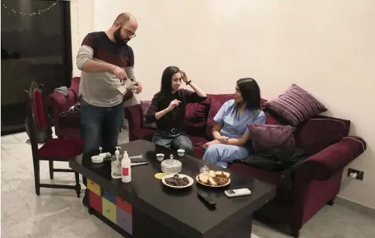  ?? BILAL HUSSEIN AP ?? Health care workers, from left, Issa Tannous, Nour Kassem and Chloe Ghosh enjoy a coffee break at their temporary apartment provided by the Lebanese group Baytna Baytak (Arabic for Our Home Is Your Home) in Beirut.