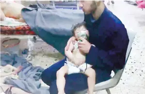  ?? (AFP) ?? An image grab taken from a video released by the Syrian Civil Defence in Douma shows an unidentifi­ed volunteer holding an oxygen mask over a child’s face at a hospital following an alleged chemical attack on the rebel-held town.