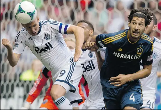  ?? — THE CANADIAN PRESS ?? Vancouver Whitecaps’ Kenny Miller, left, gets his head on a Los Angeles Galaxy corner kick as the Galaxy’s Omar Gonzalez watches during Saturday’s game at B.C. Place. Miller was upbeat about the Caps’ performanc­e despite their loss Saturday.