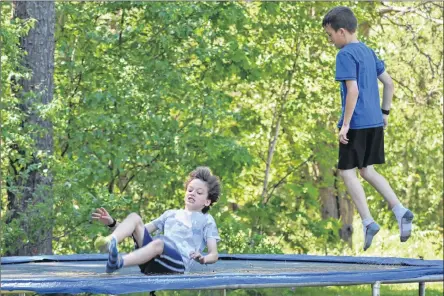 ?? ASHLEY THOMPSON ?? Aiden and Parker Francis have some fun on their trampoline. The eight-year-old twins are among the Kingston District School students slated to lose the bus service, and become walkers, in September.
