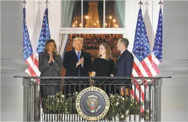  ?? Alex Brandon / Associated Press ?? First lady Melania Trump and President Trump applaud new Supreme Court Justice Amy Coney Barrett as they stand with her and her husband, Jesse Barrett, on a White House balcony after she was sworn in.